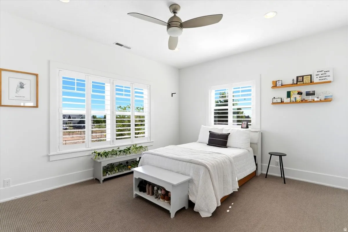 Bright interior room featuring a large window with white plantation shutters, recessed lighting, and a ceiling fan