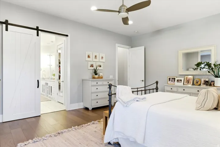 Spacious room featuring wood-finish flooring, a contemporary ceiling fan with integrated lighting, and light gray wall paint