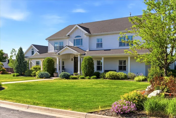 White siding exterior with a dark shingle roof, featuring a covered front porch, an arched entry, and a prominent gable