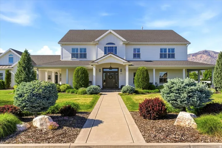 White two-story residence with a covered front porch and dark shingle roofing