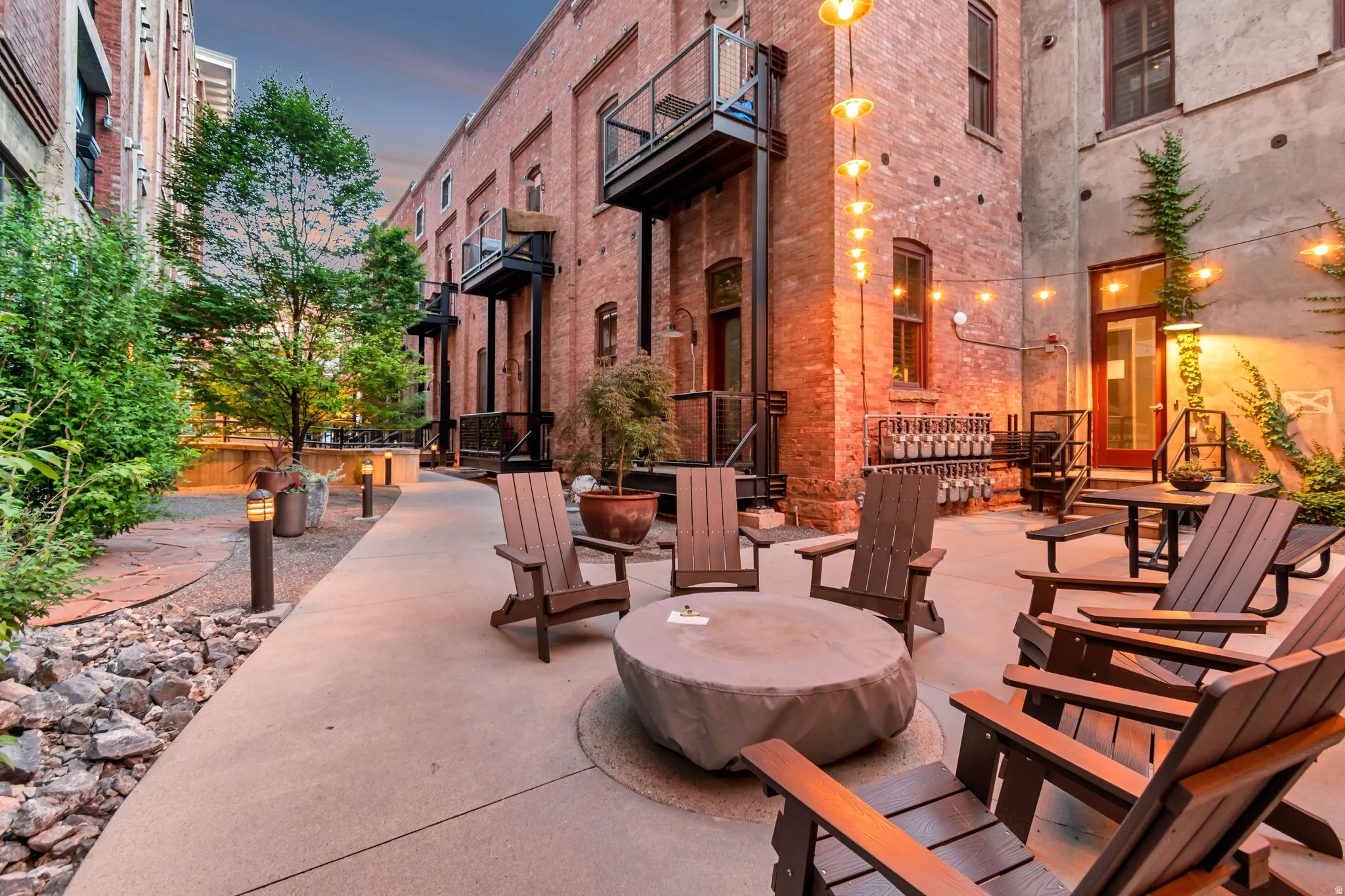 Inviting patio area featuring concrete paving, string lighting, and mature landscaping