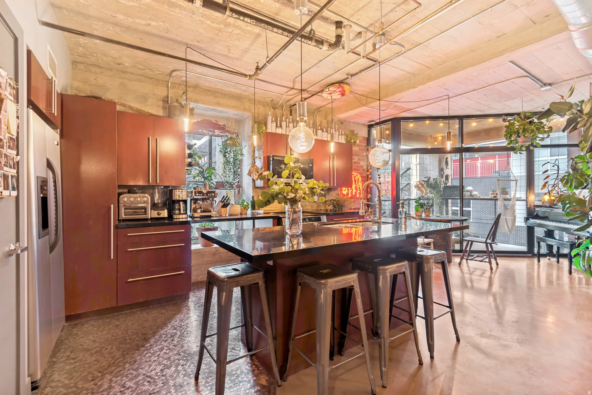 Modern kitchen featuring deep red cabinetry, a stainless steel refrigerator, and a dark island with seating