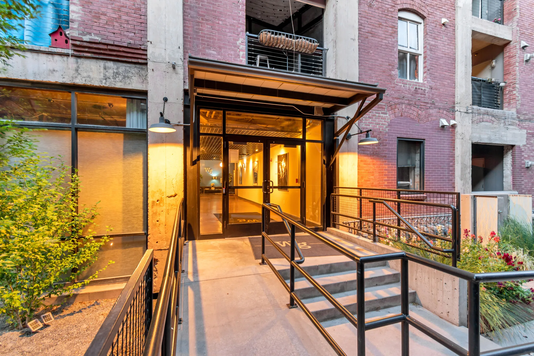 Building entrance featuring a contemporary glass door, metal awning, and exterior lighting
