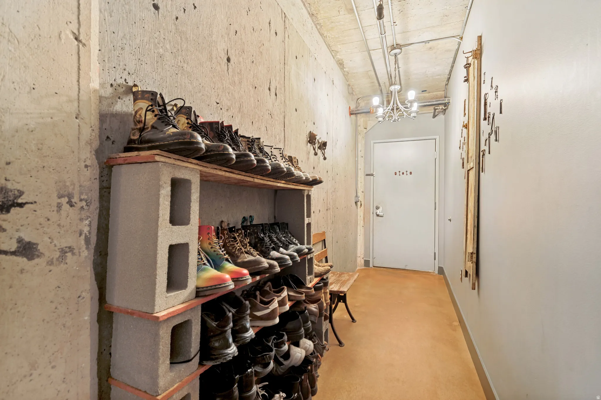 Industrial-style hallway featuring concrete walls and exposed ceiling piping