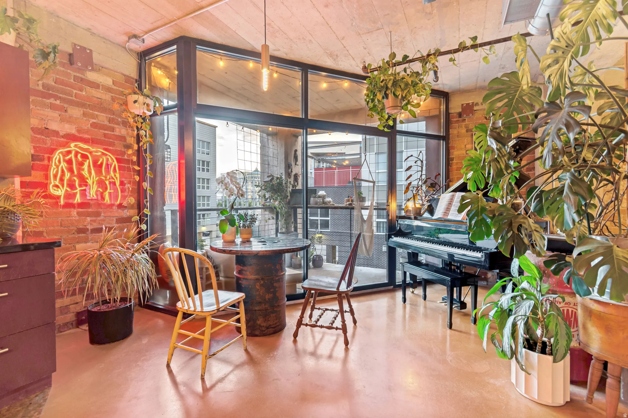 Exposed brick wall with a full-height window wall, concrete ceiling, and warm-toned flooring