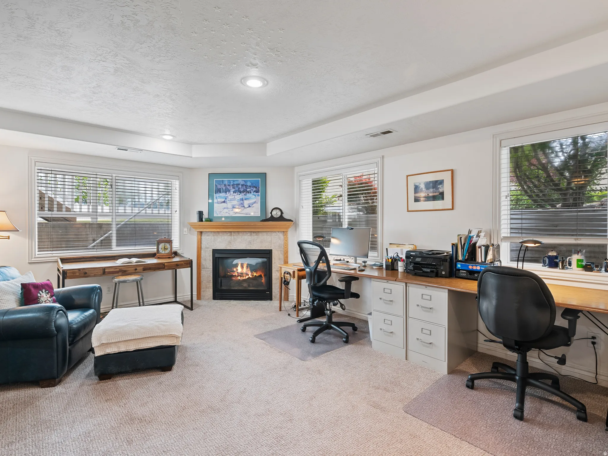 Living area featuring a gas fireplace with a stone surround and wood mantel, recessed lighting, and multiple windows with blinds