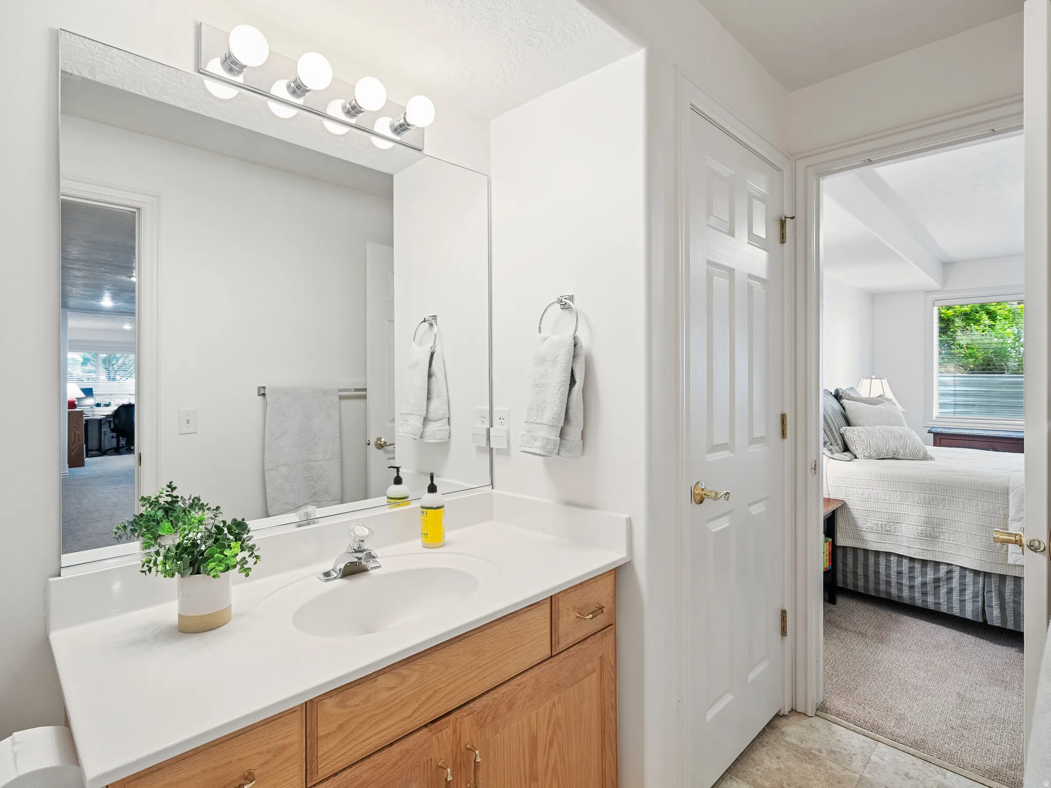 Bathroom vanity featuring a white countertop with an integrated oval sink and a chrome-finish faucet