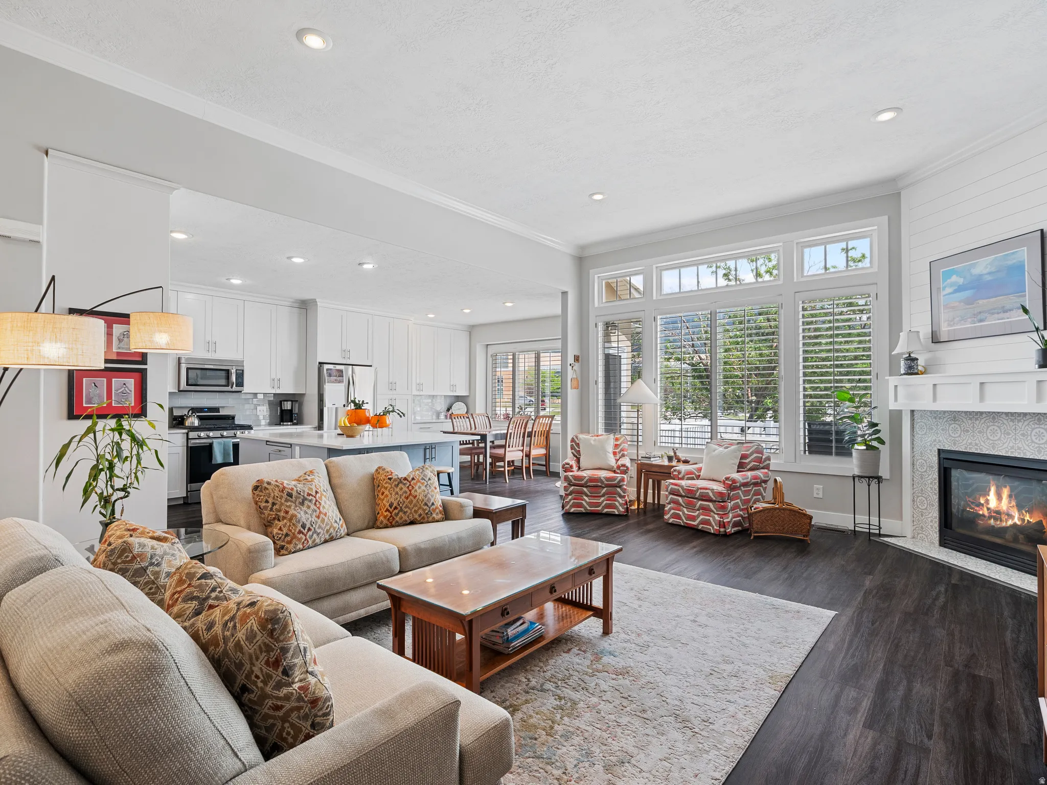 Open-concept living area featuring dark wood-finish flooring, recessed lighting, and crown molding