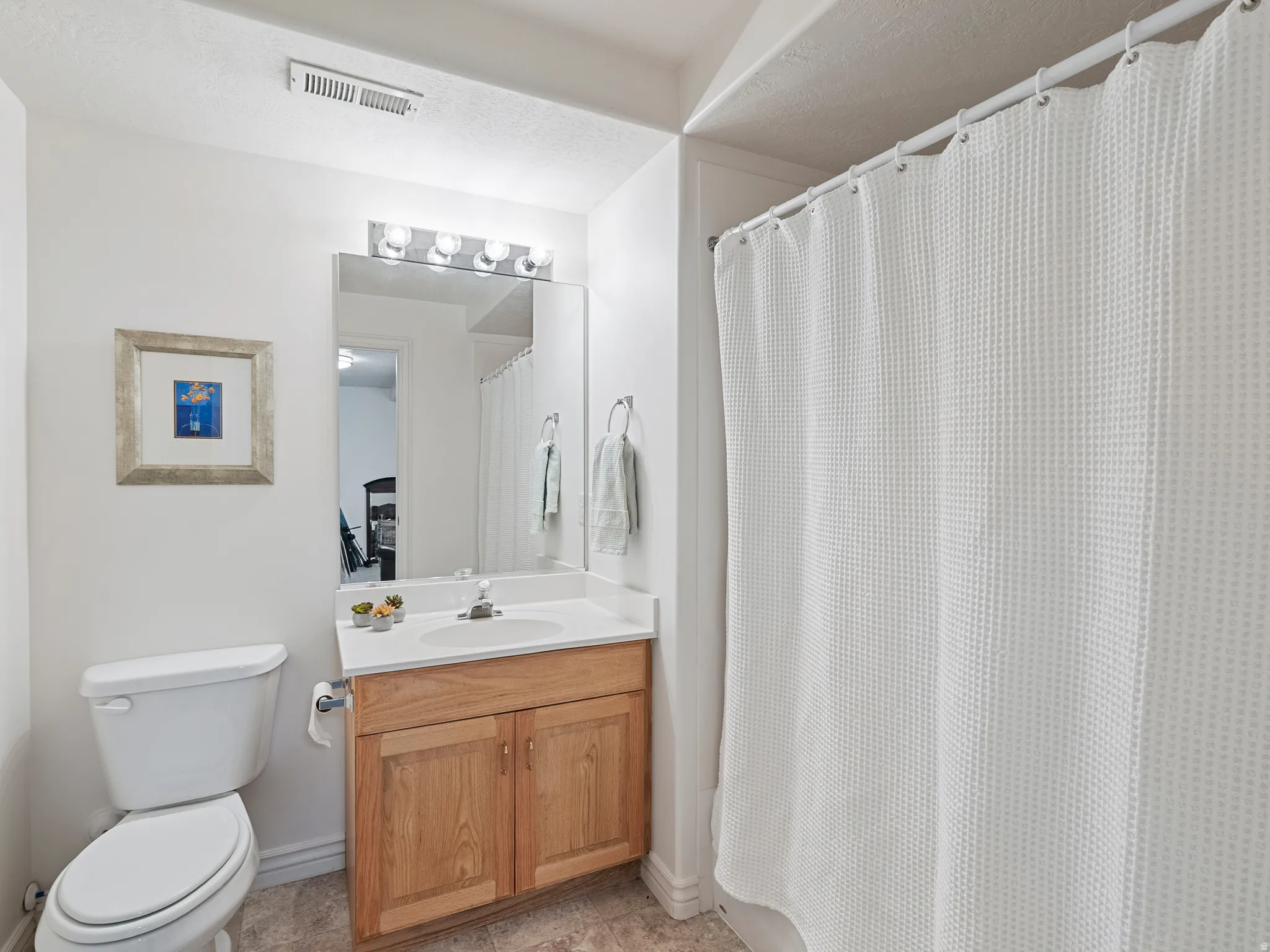 Bathroom featuring a single vanity with wood-finish cabinetry, a white countertop, and a white basin sink