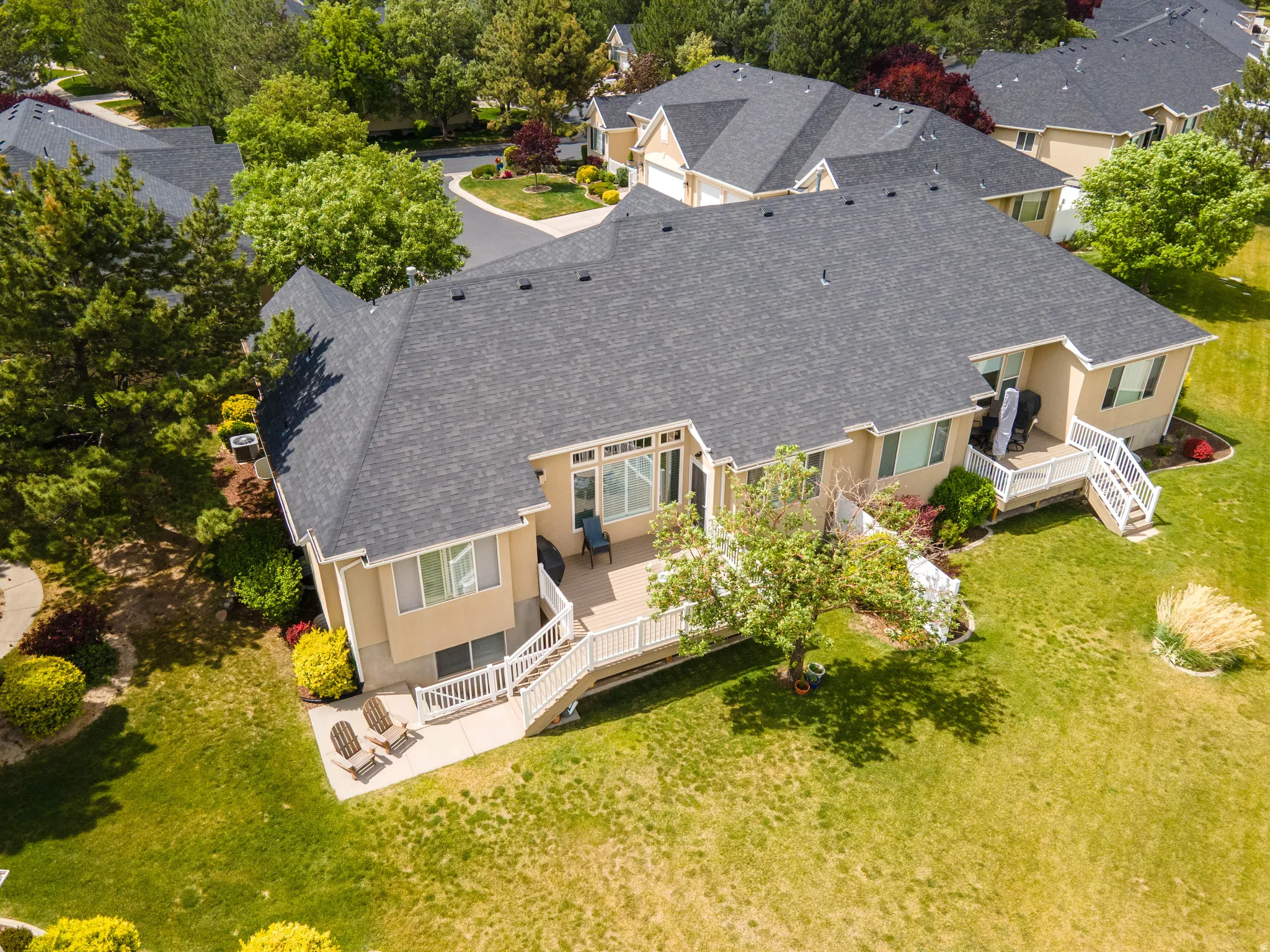 Rear exterior featuring a spacious deck with white railings, multiple windows providing ample natural light, and a lower-level patio