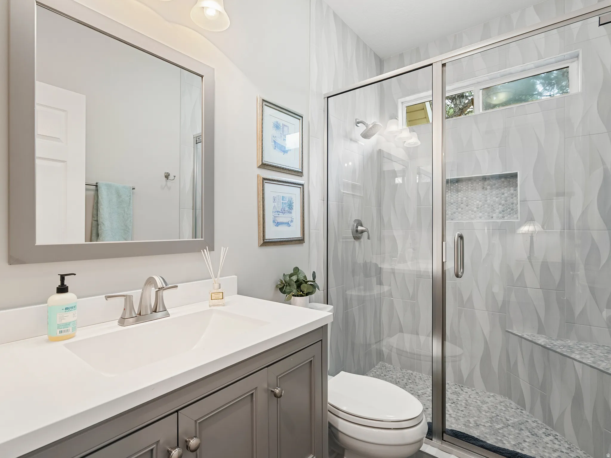 Bathroom featuring a glass-enclosed shower with textured wall tile and a mosaic-tiled niche