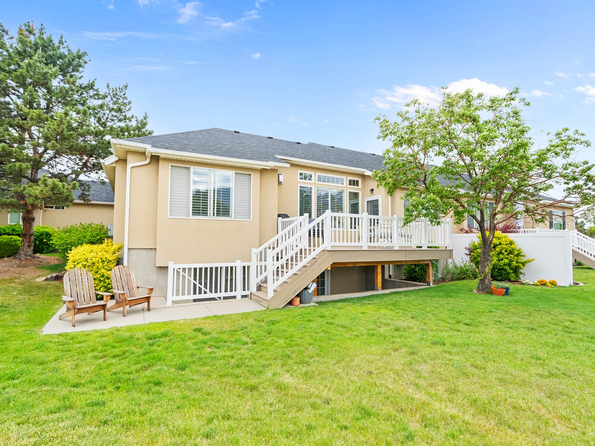 Expansive lawn with a raised deck, white railings, and mature trees