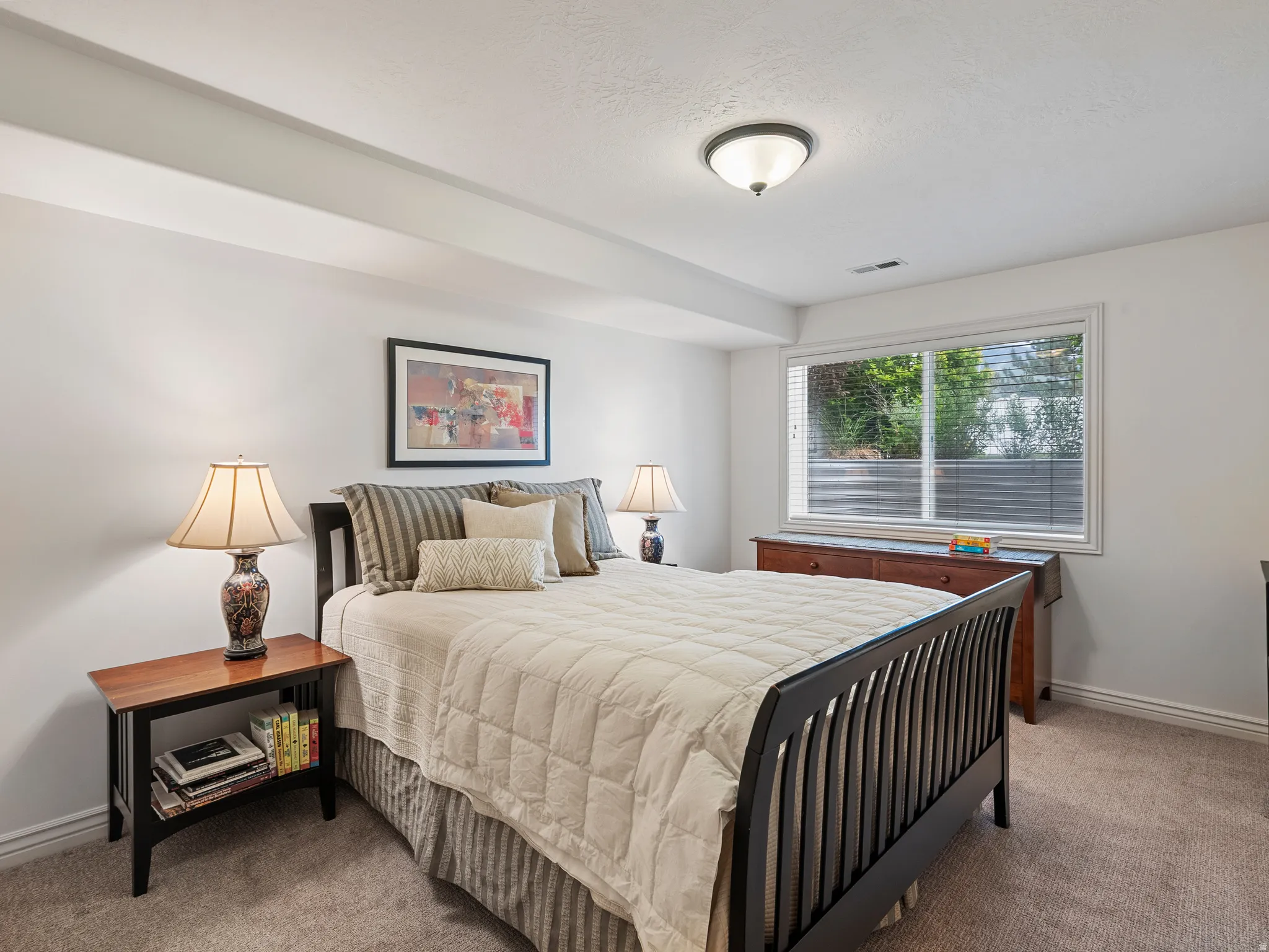 Carpeted room featuring a large window with blinds, white walls, and a ceiling-mounted light fixture