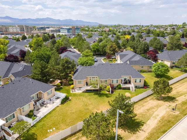 Rear exterior featuring a spacious patio, white picket fencing, and mature landscaping