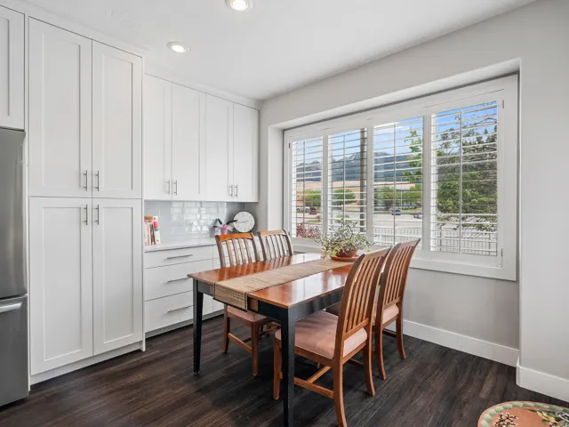 Dining area featuring white shaker-style cabinetry, a white subway tile backsplash, and a large window with white plantation shutters