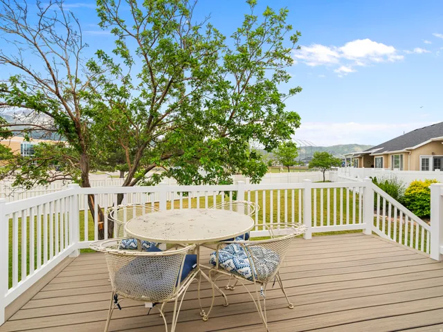 Outdoor deck featuring composite decking, white railing, and a mature tree