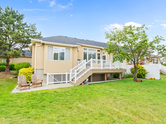 Expansive lawn with a raised deck, white railings, and mature trees