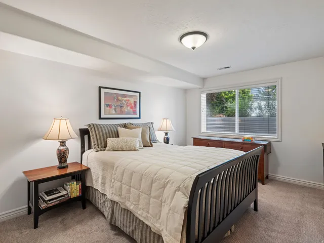 Carpeted room featuring a large window with blinds, white walls, and a ceiling-mounted light fixture