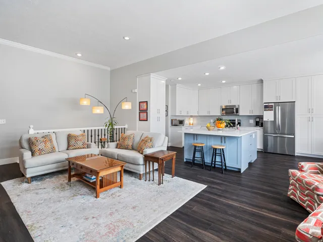 Open-concept living area featuring dark wood-finish flooring, recessed lighting, and crown molding
