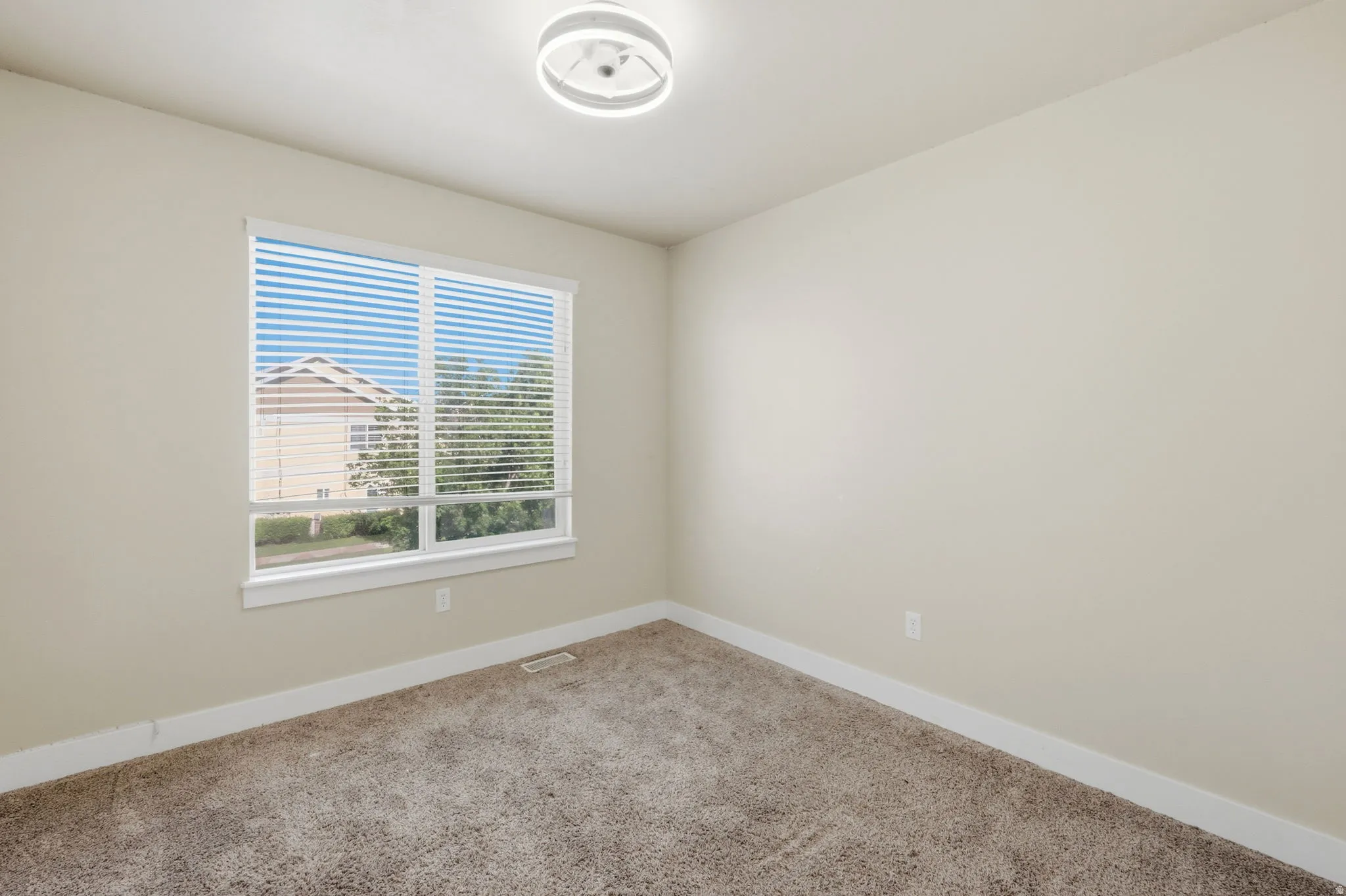 Neutral toned room featuring a large window with horizontal blinds, providing natural light