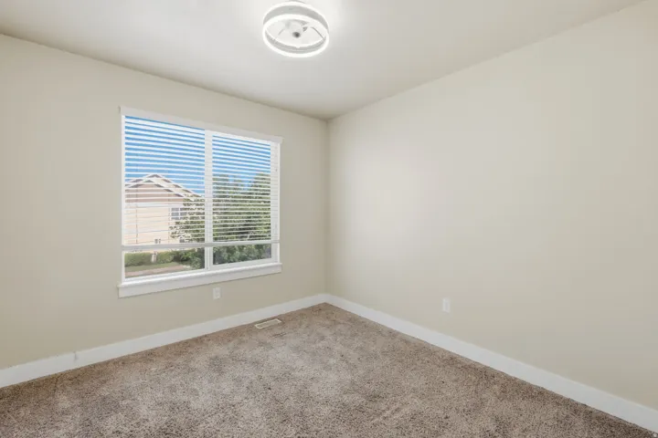 Neutral toned room featuring a large window with horizontal blinds, providing natural light