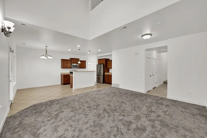 Open-concept layout with high ceilings and a kitchen featuring wood-finish cabinetry, stainless steel appliances, and a central island