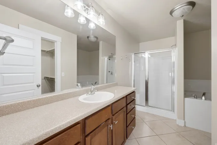 Bathroom vanity featuring a single basin sink, laminate countertop, and wood-finish cabinetry