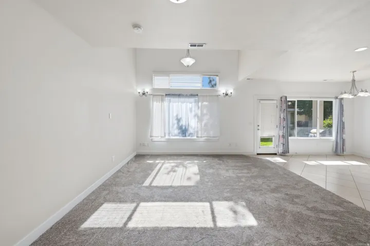 Spacious interior room featuring light gray carpet flooring transitioning to light-toned tile