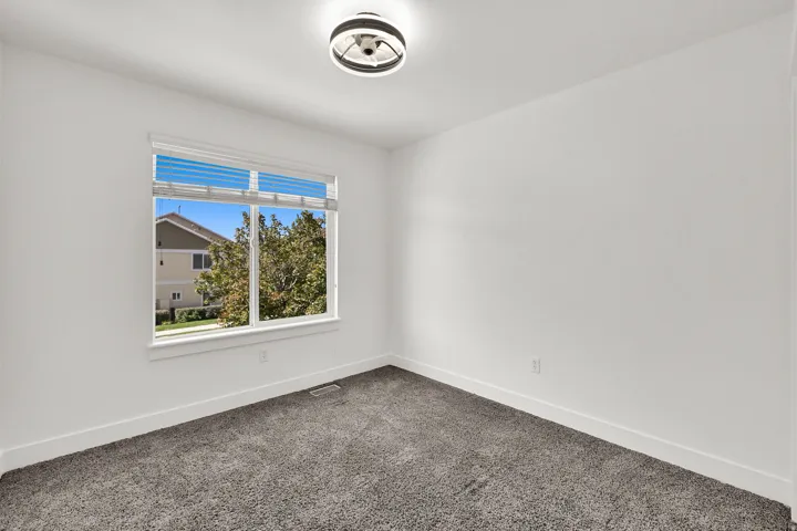 White walls, window with blinds, overhead lighting, and carpeted flooring