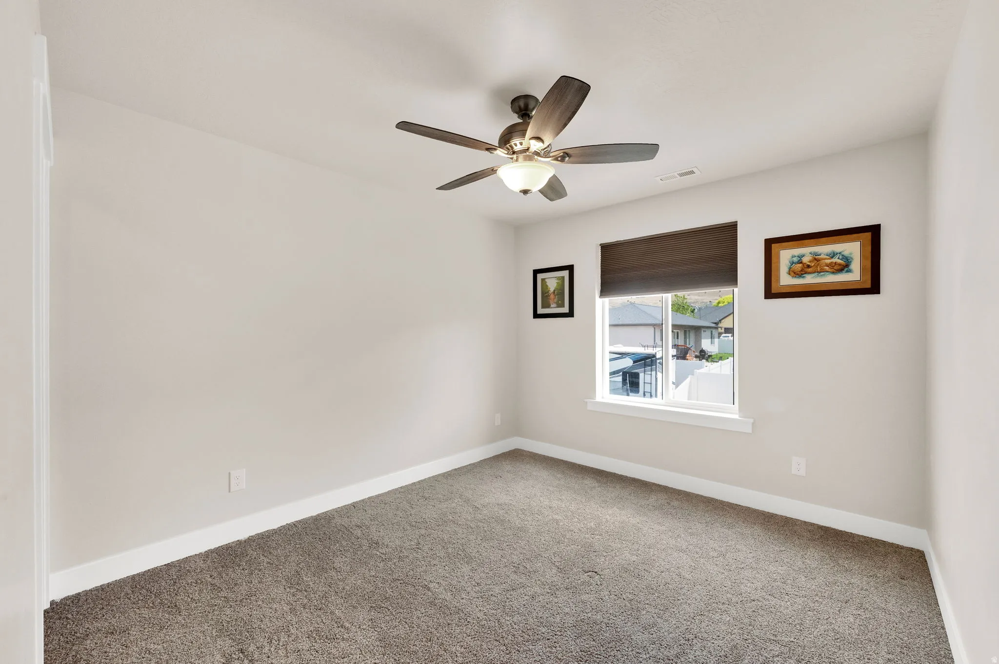 Neutral-toned room featuring plush carpet flooring and a ceiling fan with integrated lighting