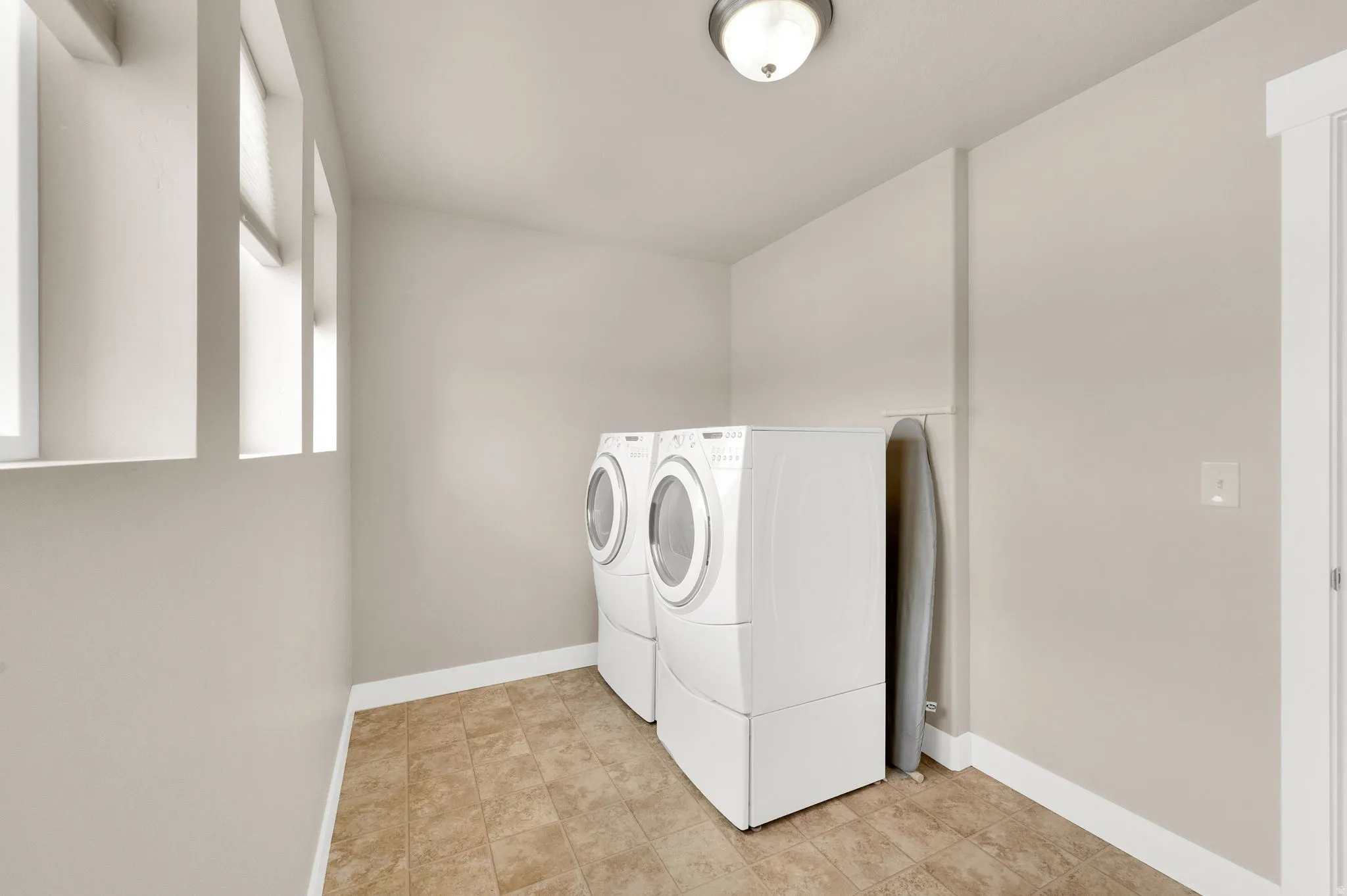 Dedicated laundry space featuring neutral-toned walls and durable tile flooring