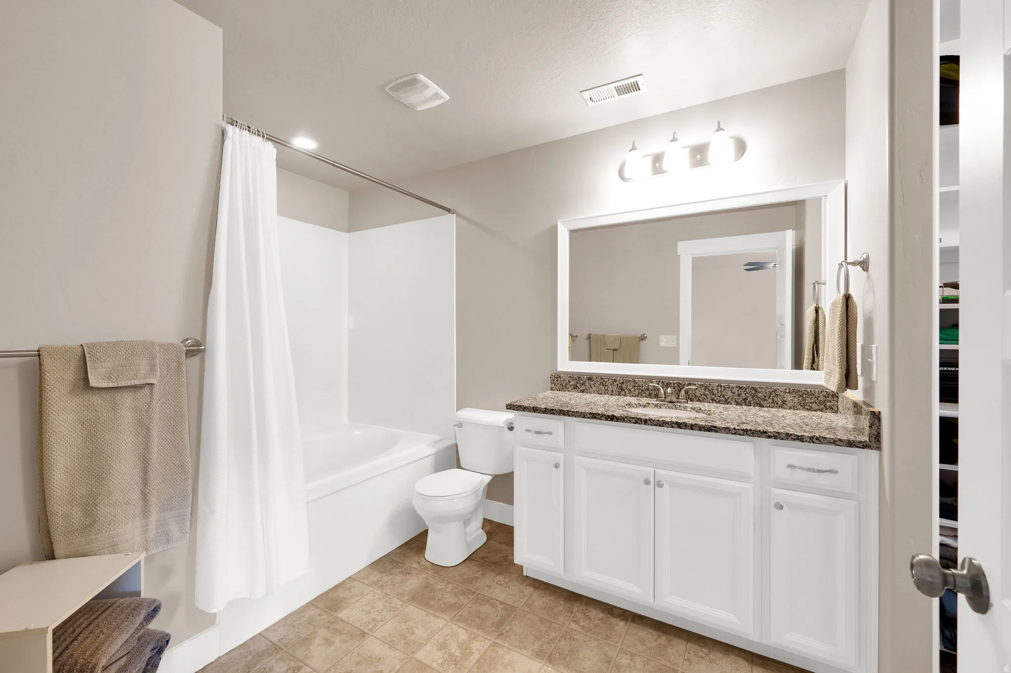 Bathroom featuring a white vanity with a dark speckled countertop, an undermount sink, and a framed mirror