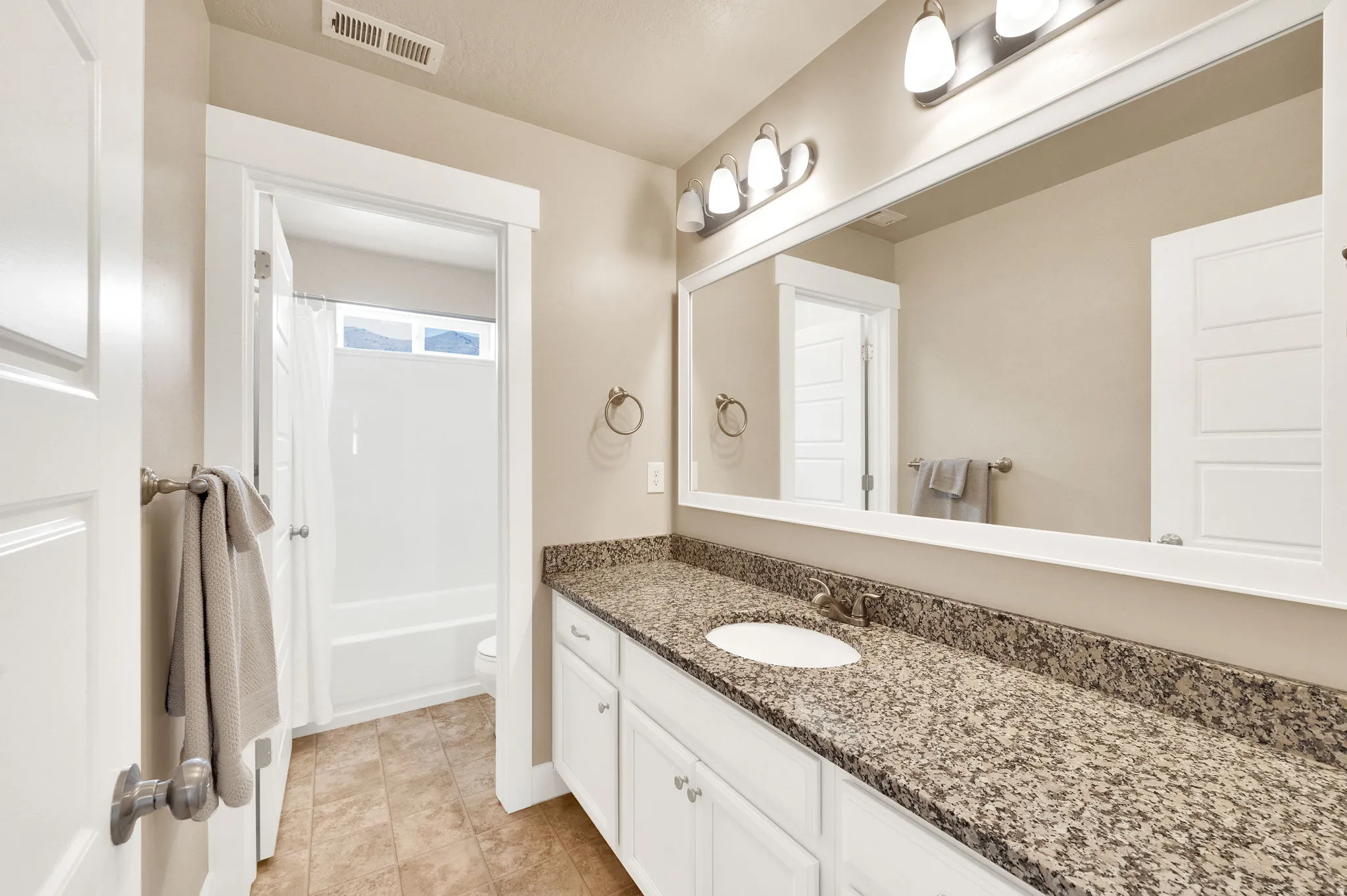 Bathroom vanity featuring a speckled countertop, undermount sink, and white cabinetry