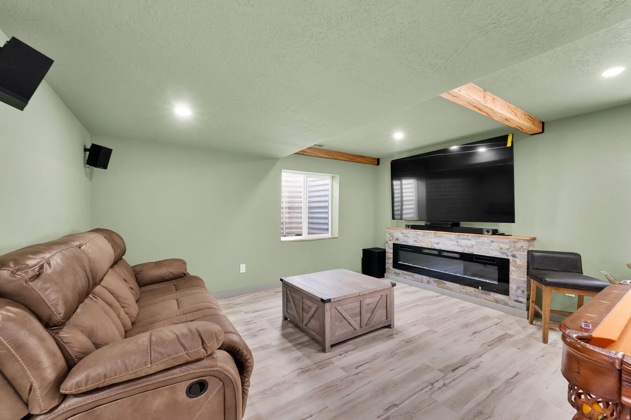 Recreational room featuring wood-finish flooring, recessed lighting, and a stone-clad linear electric fireplace