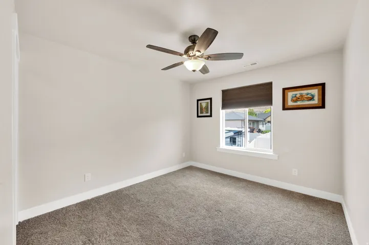 Neutral-toned room featuring plush carpet flooring and a ceiling fan with integrated lighting
