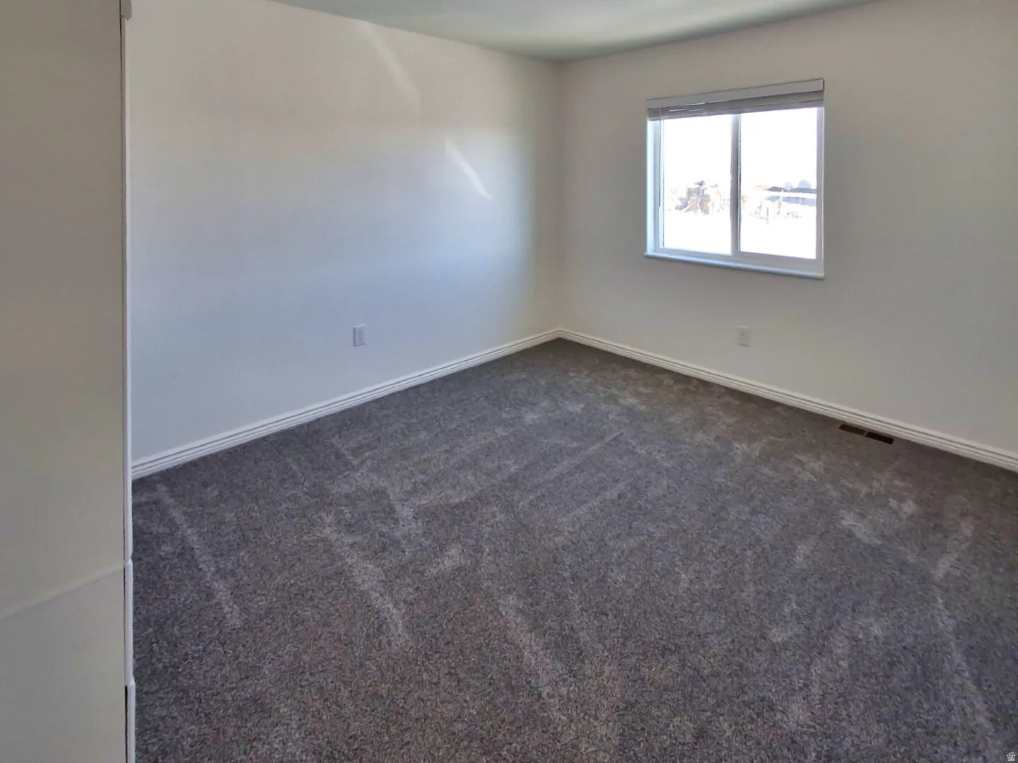 Carpeted interior room with white walls, white trim, and a double-pane window
