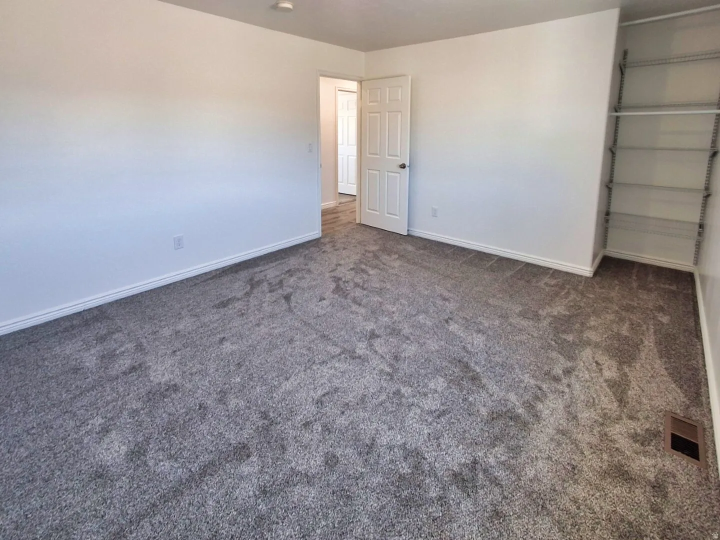 Neutral tone walls with gray carpeting, white baseboards, and a built-in closet system