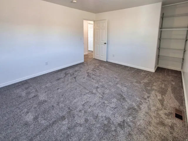 Neutral tone walls with gray carpeting, white baseboards, and a built-in closet system