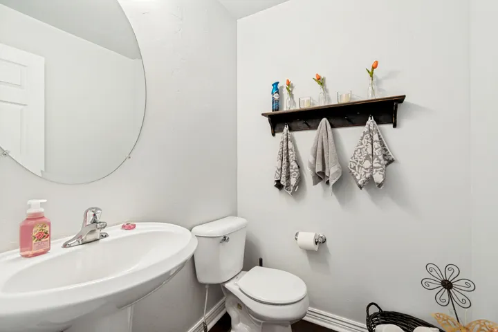 Pedestal sink with chrome faucet, complemented by an oval wall-mounted mirror