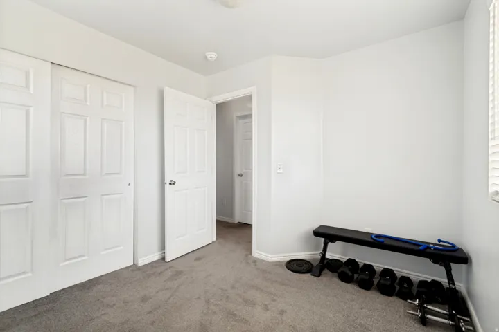Bedroom featuring neutral-toned walls, gray carpet flooring, and white paneled bi-fold closet doors