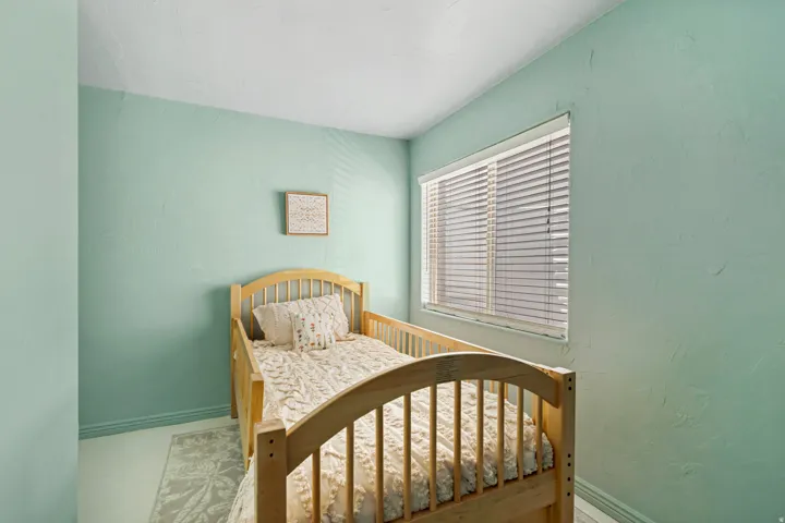 Bedroom featuring light green walls, a single window with horizontal blinds, and baseboard trim