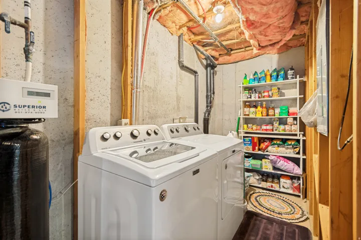 Laundry area featuring a top-load washing machine, front-load dryer, exposed concrete walls, and visible ceiling insulation