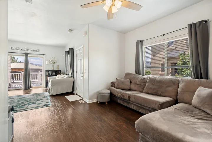 Living space featuring wood-finish flooring, white walls, and a ceiling fan with integrated lighting