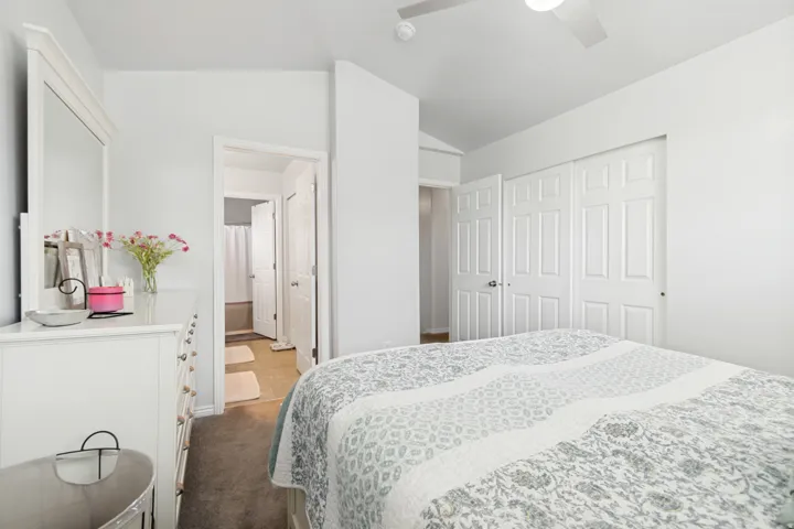 Bedroom featuring a ceiling fan, carpet flooring, a built-in closet with bi-fold doors, and a doorway to an adjoining bathroom