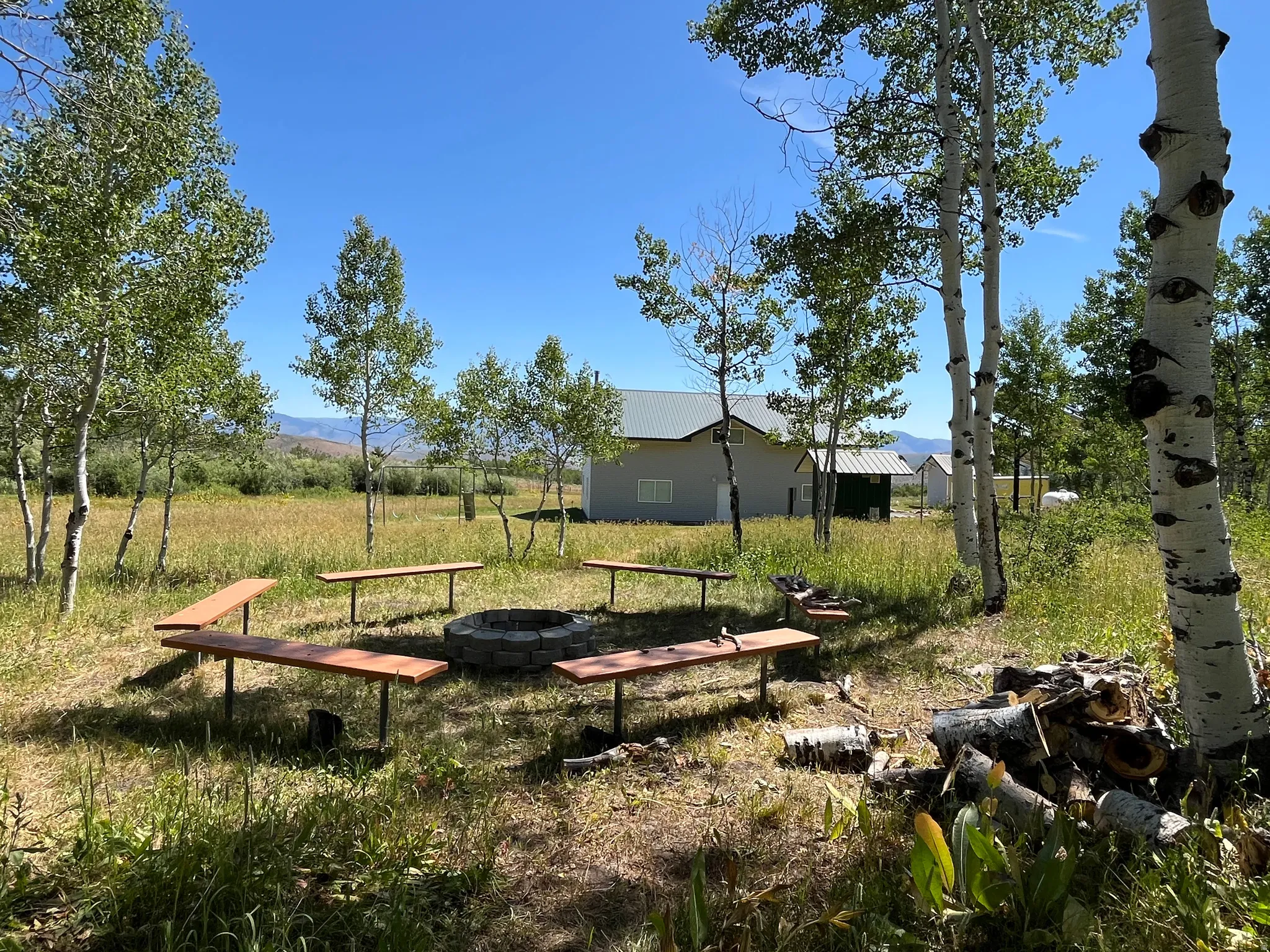 Outdoor fire pit area featuring a stone-lined fire pit and surrounding wooden benches
