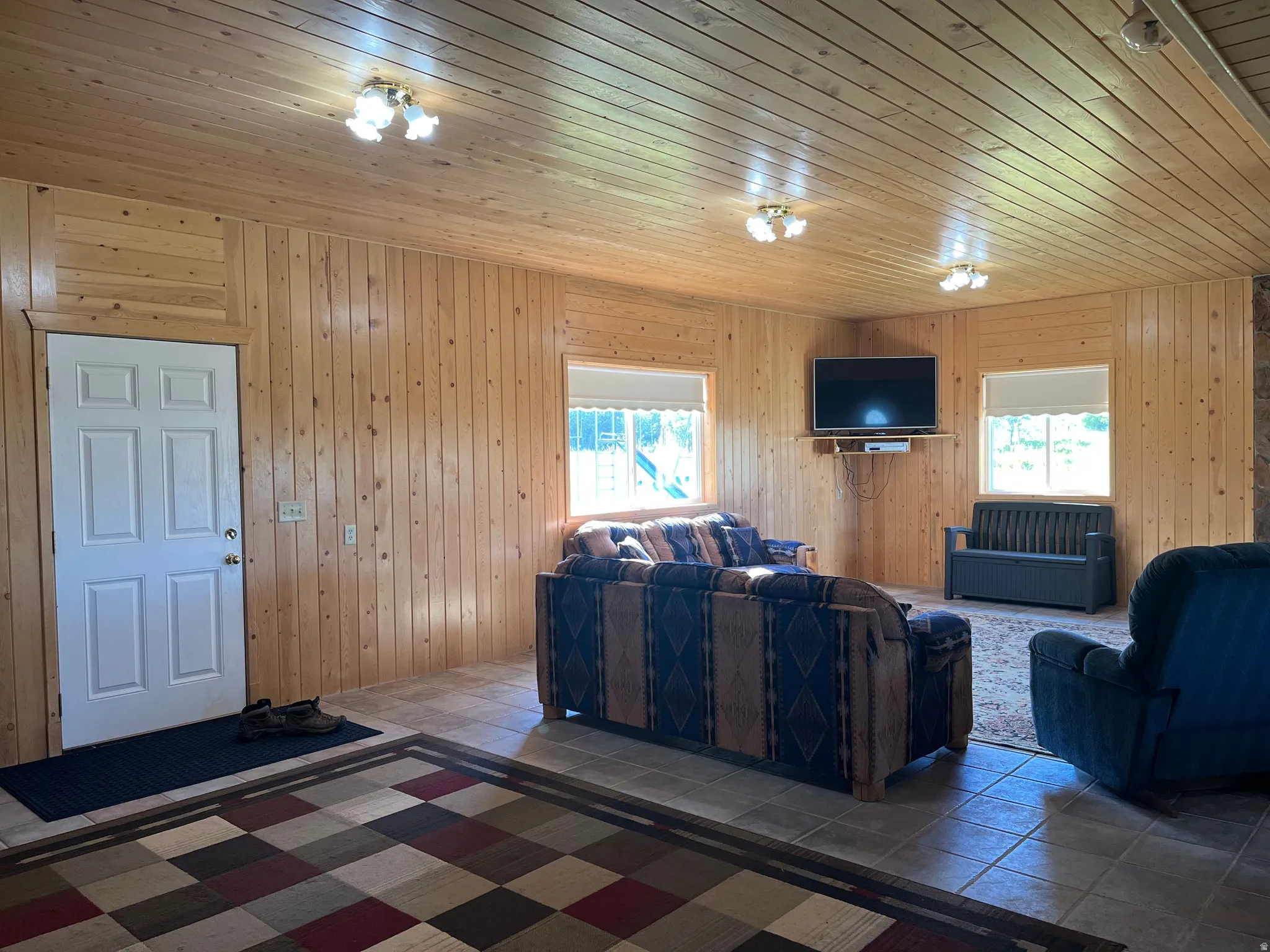 Wood-paneled living space featuring light wood wall and ceiling finishes