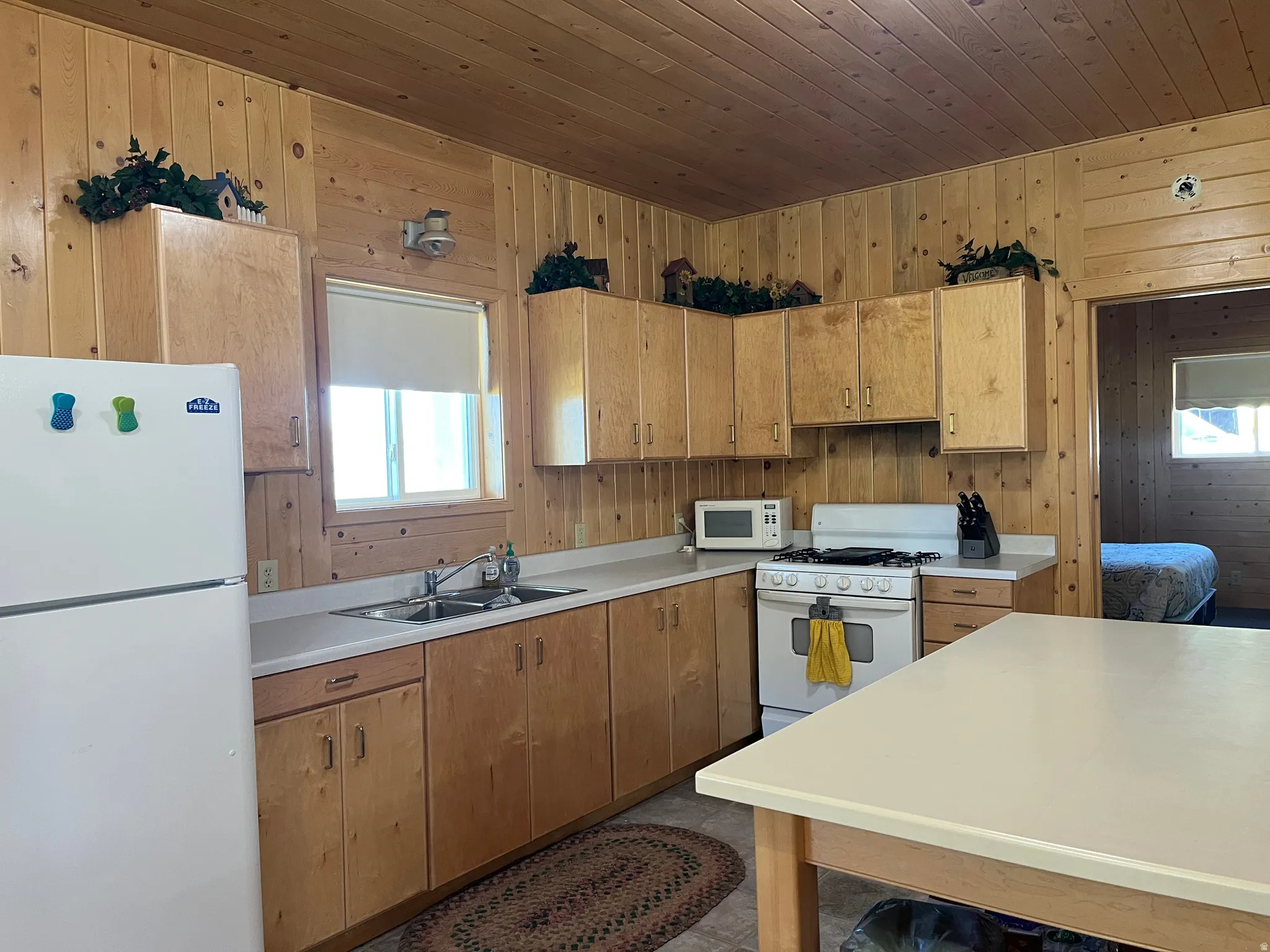 Kitchen featuring wood paneling, wood-finish cabinetry, and a double basin sink