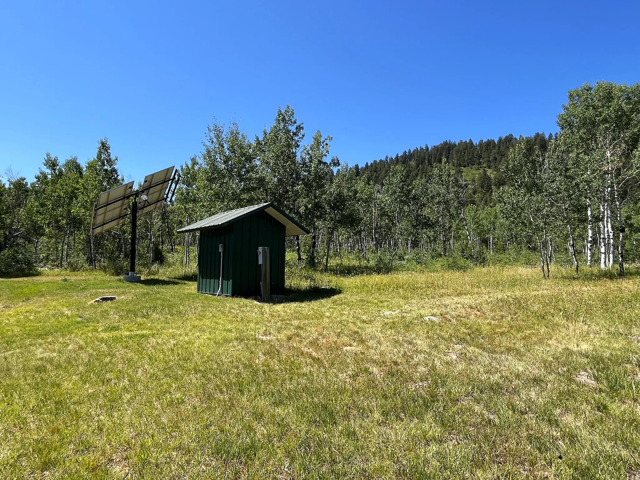 Expansive outdoor area featuring a compact utility shed with a metal roof and a multi-panel solar array