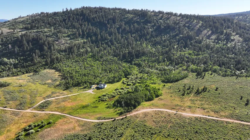 Expansive property featuring a single-story residence and a winding unpaved drive