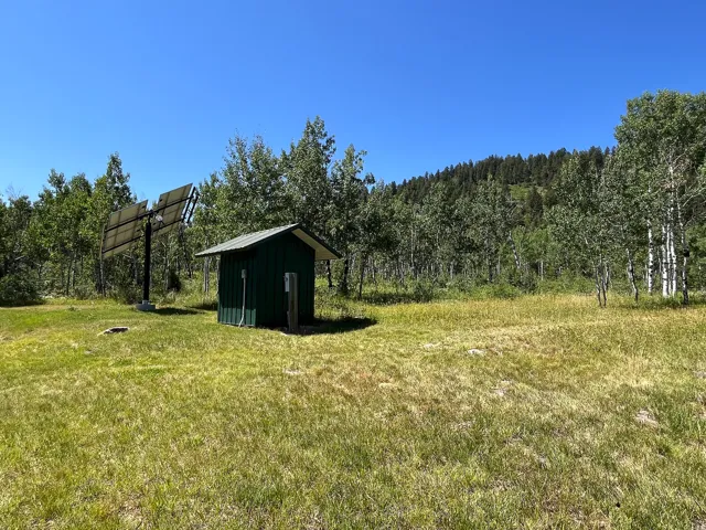 Expansive outdoor area featuring a compact utility shed with a metal roof and a multi-panel solar array